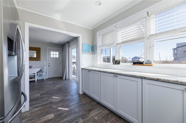 kitchen featuring crown molding, stainless steel fridge with ice dispenser, light countertops, white cabinets, and dark wood-type flooring