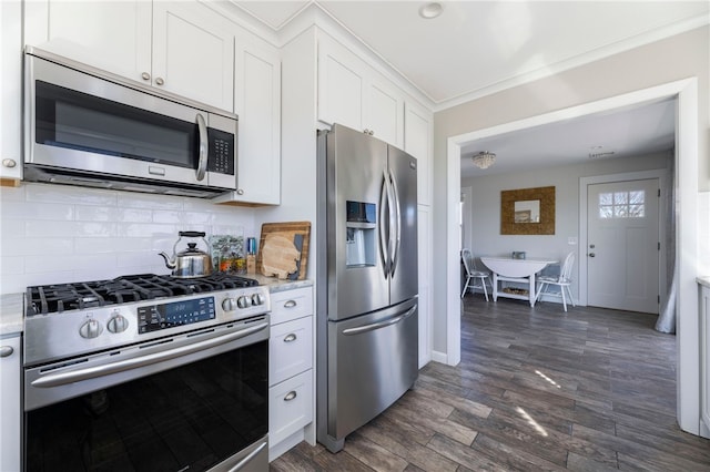 kitchen featuring stainless steel appliances, dark wood finished floors, baseboards, backsplash, and white cabinetry
