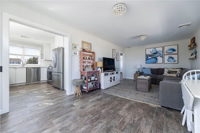 living area featuring ornamental molding, wood finished floors, and visible vents