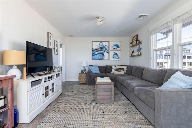 living area with wood finished floors, visible vents, and baseboards