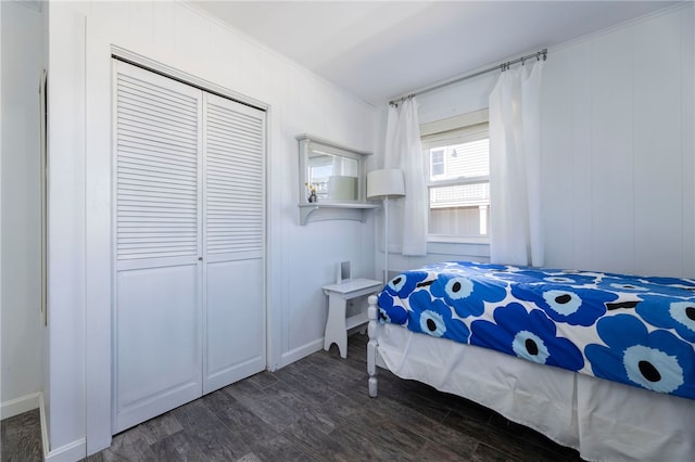 bedroom with ornamental molding, dark wood-type flooring, a decorative wall, a closet, and baseboards