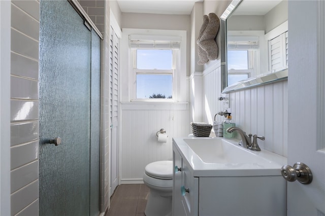 full bath with a wainscoted wall, wood finished floors, an enclosed shower, toilet, and vanity