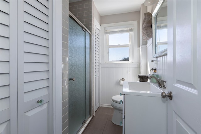 bathroom featuring toilet, wainscoting, a stall shower, tile patterned flooring, and vanity