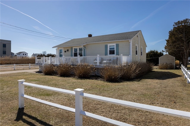 ranch-style home featuring a chimney, a front lawn, fence, and a shingled roof