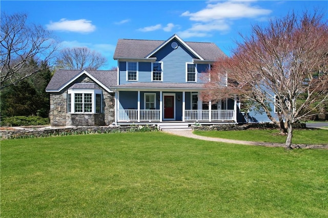 view of front of house with covered porch, a front yard, a shingled roof, and stone siding