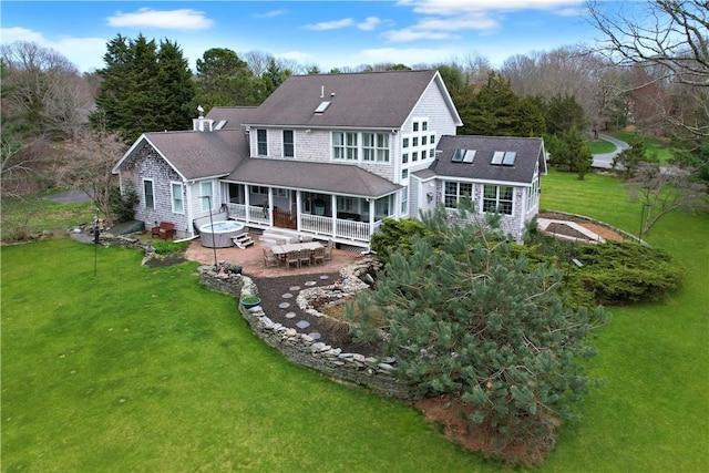 rear view of house featuring a lawn, a patio area, and a shingled roof