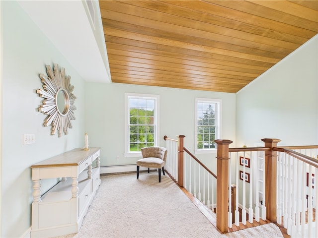 sitting room featuring carpet flooring, wooden ceiling, baseboard heating, an upstairs landing, and baseboards