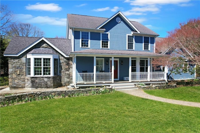 view of front facade featuring a front yard, a porch, stone siding, and roof with shingles