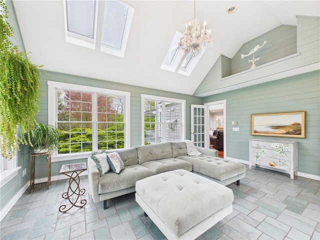 living room featuring a skylight, a chandelier, high vaulted ceiling, stone tile floors, and baseboards