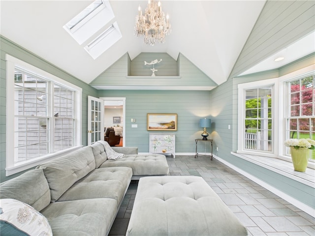 living room featuring vaulted ceiling, baseboards, a skylight, a chandelier, and wood walls