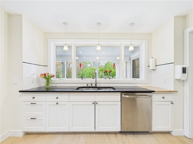 kitchen featuring stainless steel dishwasher, a sink, tasteful backsplash, white cabinets, and decorative light fixtures