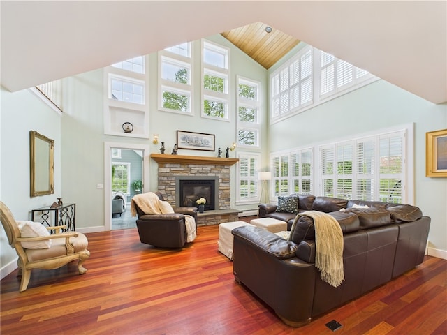 living room with high vaulted ceiling, baseboards, wood finished floors, and a stone fireplace