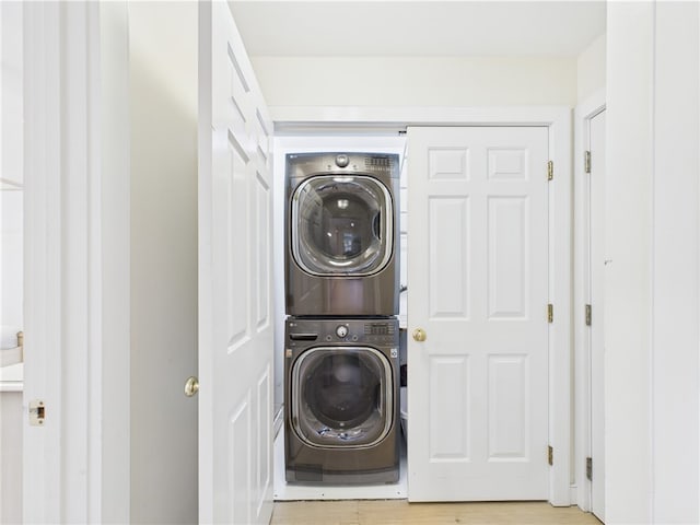 laundry area with stacked washer / drying machine and light wood-style flooring