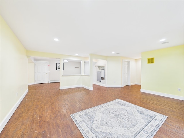unfurnished living room featuring baseboard heating, baseboards, wood finished floors, and recessed lighting