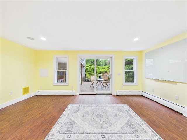 unfurnished living room with a baseboard heating unit, wood finished floors, baseboards, and recessed lighting
