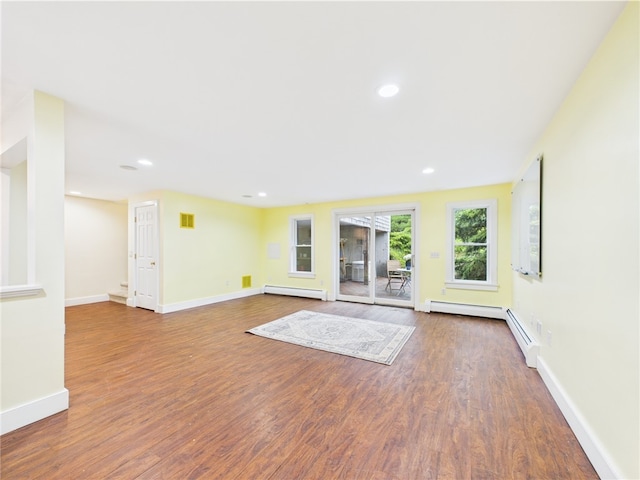 unfurnished living room featuring a baseboard heating unit, wood finished floors, baseboards, and recessed lighting