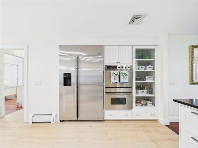 50 Intrepid Ln, Jamestown, RI 02835 - kitchen featuring stainless steel appliances, a baseboard heating unit, light wood-style flooring, dark countertops, and baseboards