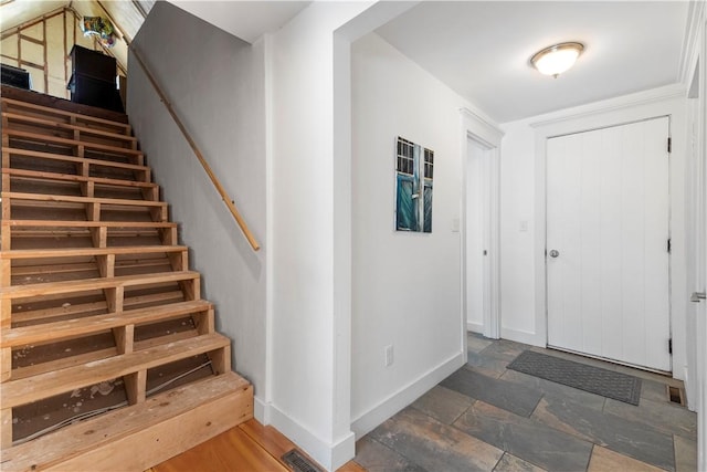 foyer with stairway, stone finish flooring, baseboards, and visible vents