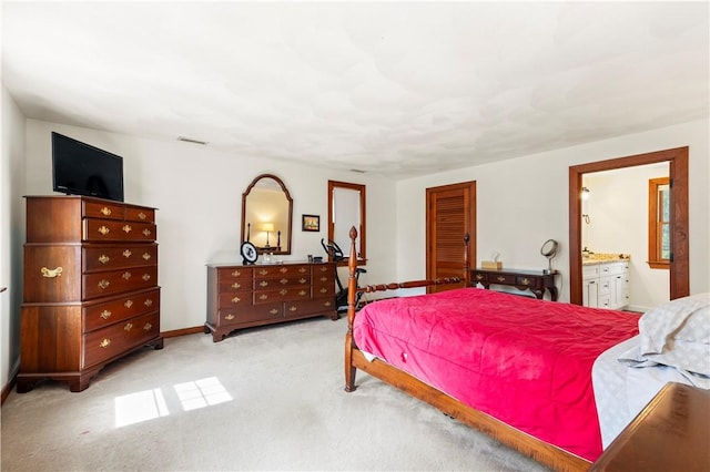 bedroom with ensuite bath, baseboards, visible vents, and light colored carpet