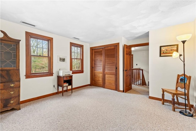 interior space with carpet, visible vents, baseboards, and an upstairs landing
