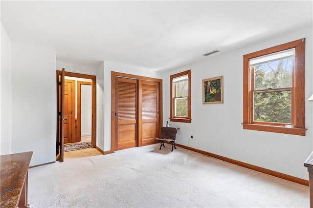 unfurnished bedroom with baseboards, visible vents, a closet, and light colored carpet