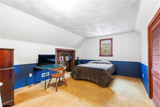 bedroom with lofted ceiling, carpet flooring, wood walls, and wainscoting