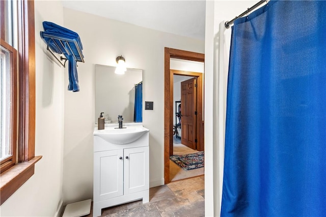 bathroom with baseboards, stone finish flooring, and vanity