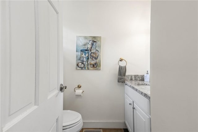 bathroom with vanity, toilet, baseboards, and visible vents