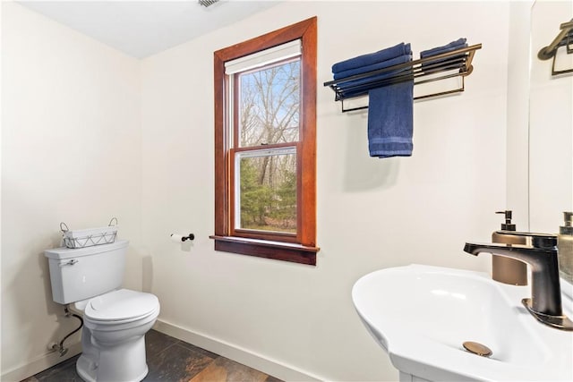 half bath featuring baseboards, a sink, and toilet