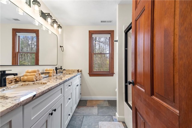 bathroom with stone tile flooring, visible vents, baseboards, and a sink