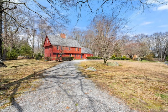 view of front of property with a chimney, driveway, a barn, and a front yard