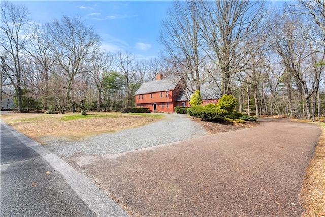 view of front facade with a chimney and driveway