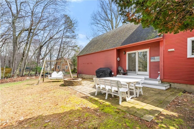 rear view of house with a fire pit, roof with shingles, a patio area, and a yard