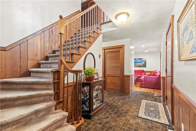 staircase with brick floor, a wainscoted wall, and wooden walls