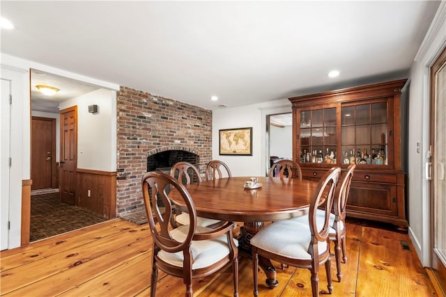 dining area featuring recessed lighting, wood walls, a wainscoted wall, light wood-type flooring, and a fireplace