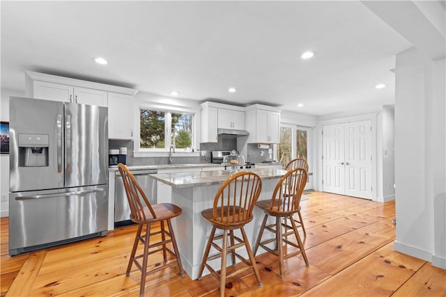 kitchen featuring stainless steel appliances, a center island, light wood-style floors, and a healthy amount of sunlight