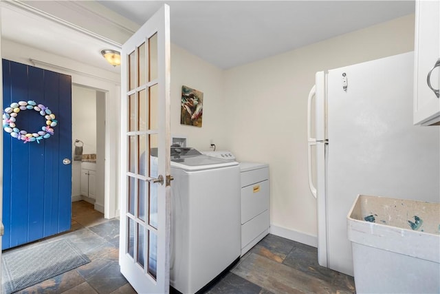 washroom featuring stone tile floors, washing machine and clothes dryer, and baseboards