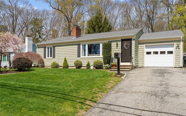 ranch-style home featuring a chimney, aphalt driveway, a front lawn, an attached garage, and roof with shingles