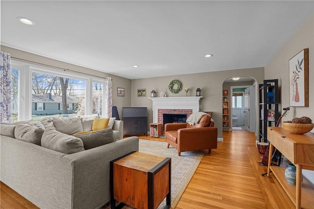 living room with light wood-style flooring, arched walkways, recessed lighting, and a fireplace