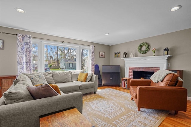 living area with recessed lighting, light wood-style floors, and a brick fireplace