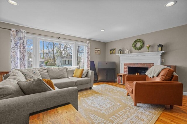 living room with baseboards, wood finished floors, a fireplace, and recessed lighting