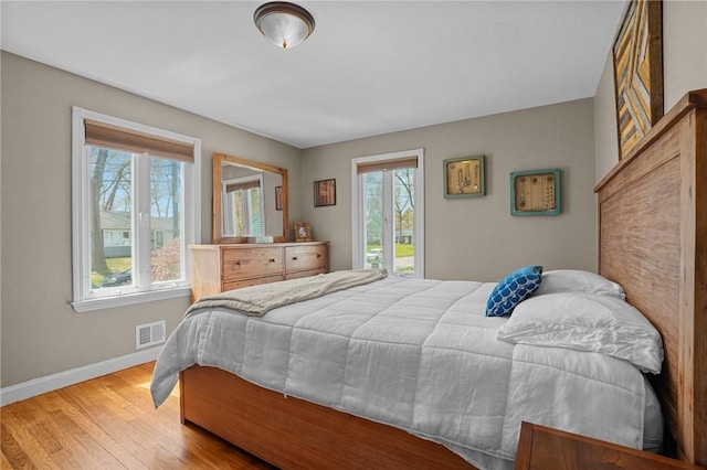 bedroom featuring wood finished floors, visible vents, and baseboards