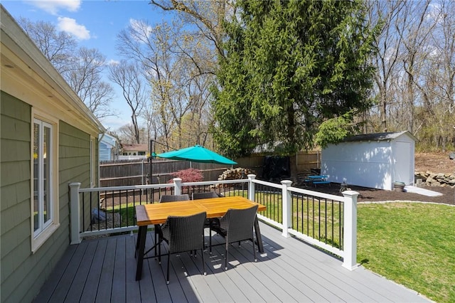 wooden terrace featuring a fenced backyard, a lawn, an outdoor structure, outdoor dining space, and a shed
