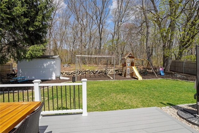 view of yard with a storage unit, an outbuilding, a playground, fence, and a deck