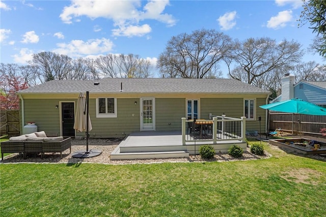 rear view of property featuring fence, a lawn, a vegetable garden, and a deck