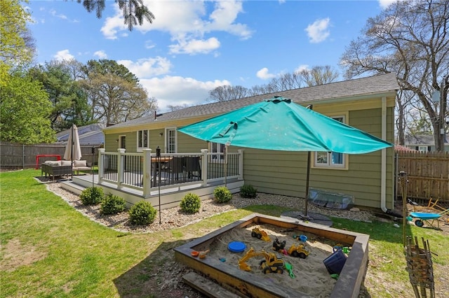 back of house with a wooden deck, a lawn, and a fenced backyard