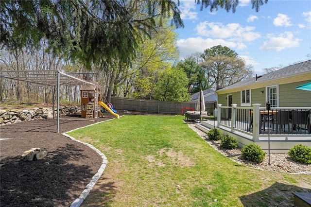 view of yard with a wooden deck, a fenced backyard, and a playground