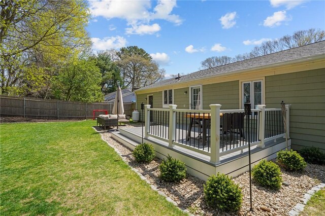 rear view of property with a lawn, a deck, a fenced backyard, an outdoor hangout area, and roof with shingles