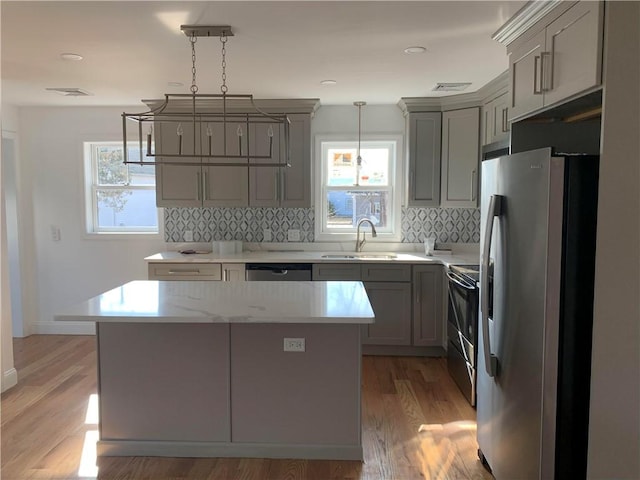 88 Reed St, Warwick, RI 02886 - kitchen featuring stainless steel appliances, gray cabinetry, backsplash, light wood-style floors, and pendant lighting