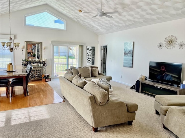 living room featuring baseboards, carpet floors, high vaulted ceiling, and ceiling fan with notable chandelier